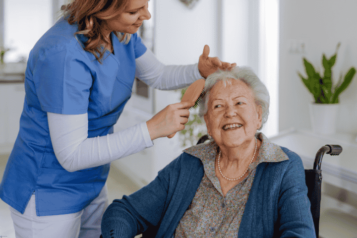 Smiling senior receiving grooming assistance from a caregiver, reflecting personal and daily living assistance and elderly care services.